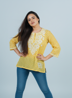 Model wearing a Yellow Chikankari Kurti made of Mulmul fabric, featuring hand-embroidered designs and a stylish fit.